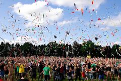 Photograph of a sea of people juggling, with very little of a field visible between legs and a blue sky filled with all kinds of objects